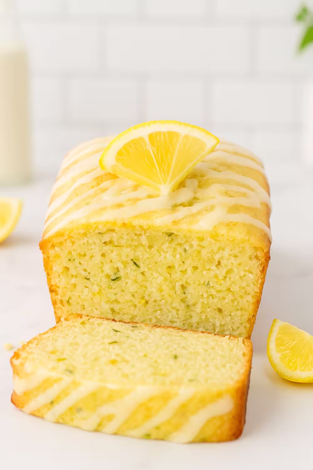 Luscious Lemon Zucchini Bread topped with a drizzle of lemon glaze and a slice of fresh lemon.