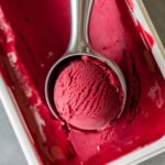 Close-up of creamy strawberry sorbet being scooped from a container