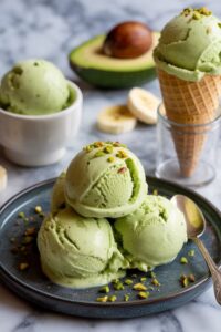 Scoops of creamy avocado and banana ice cream garnished with chopped pistachios