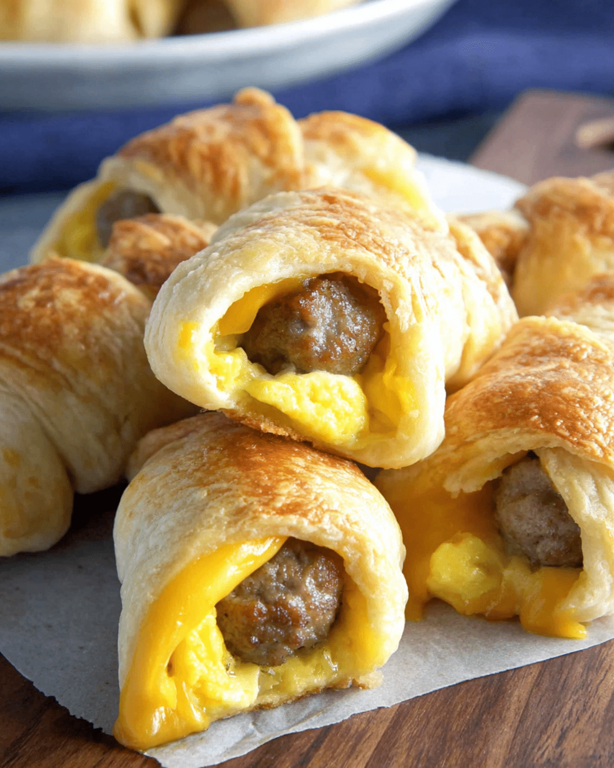 Golden brown sausage egg and cheese breakfast roll-ups with melted cheese and flaky pastry.