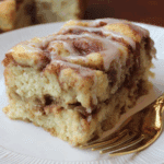 Slice of Apple Cinnamon Sheet Cake with swirls of cinnamon and a drizzle of glaze, served on a white plate with a gold fork.
