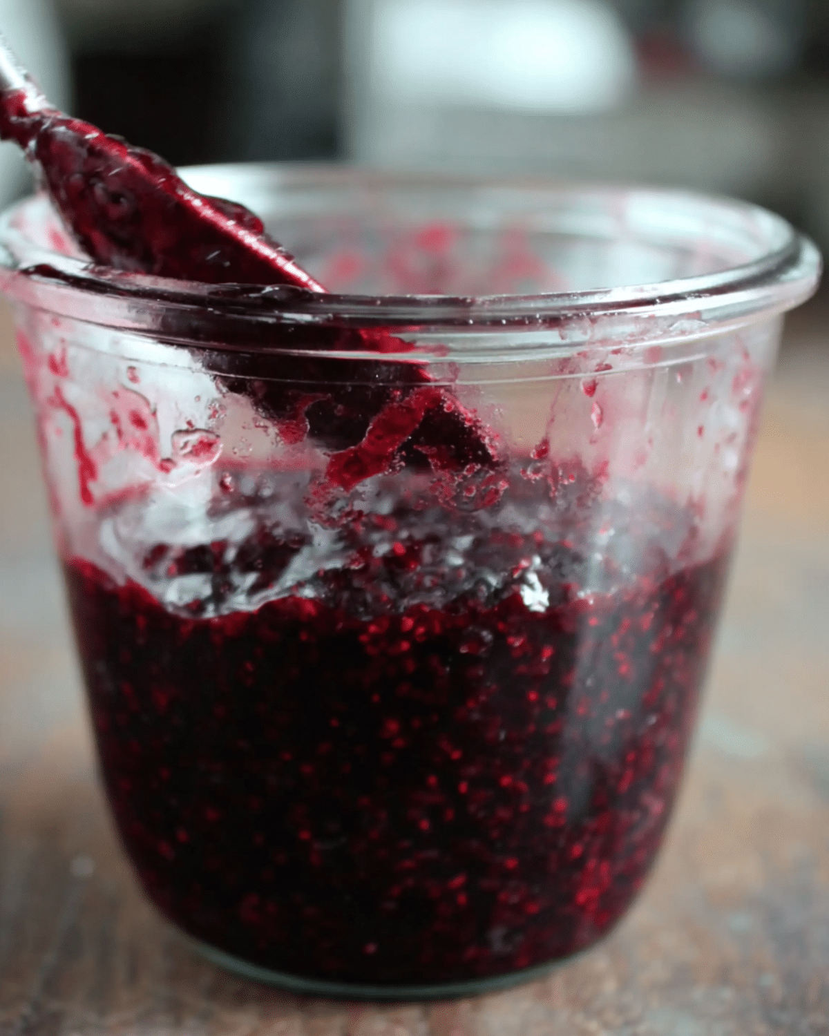Jar of black raspberry jam with a spoon, showing its rich, dark purple color and thick, seedy texture.