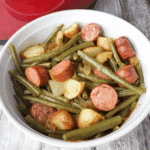A bowl of Crockpot Kielbasa and Green Beans with sliced sausage, green beans, and baby potatoes.