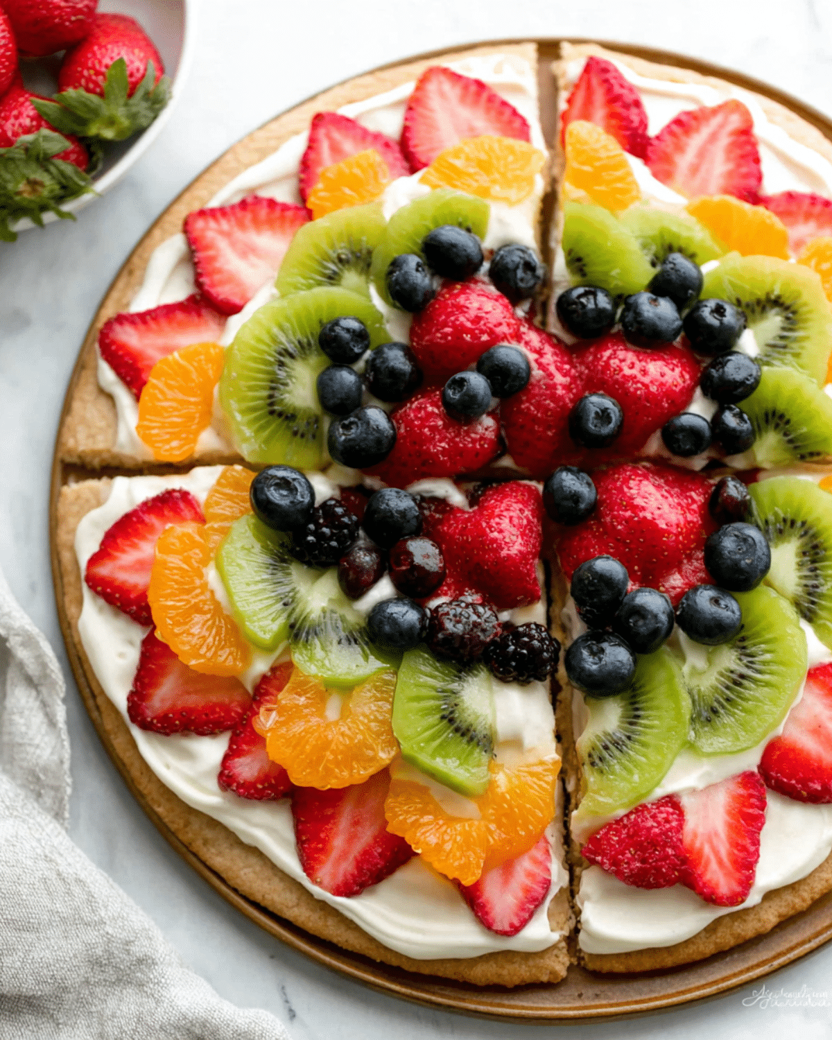 Colorful Easy Fruit and Cracker Pizzas topped with strawberries, kiwi, blueberries, blackberries, mandarin oranges, and creamy spread on a round cracker base.