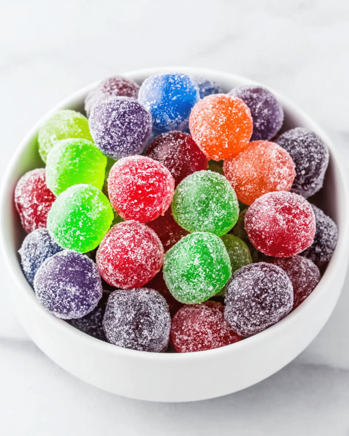 Bowl filled with colorful Kool-Aid Grapes coated in sugar, featuring red, green, purple, blue, and orange hues.