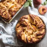 Freshly baked Peach Brioche in round and loaf pans, featuring golden swirls of dough and slices of peaches nestled in the bread.